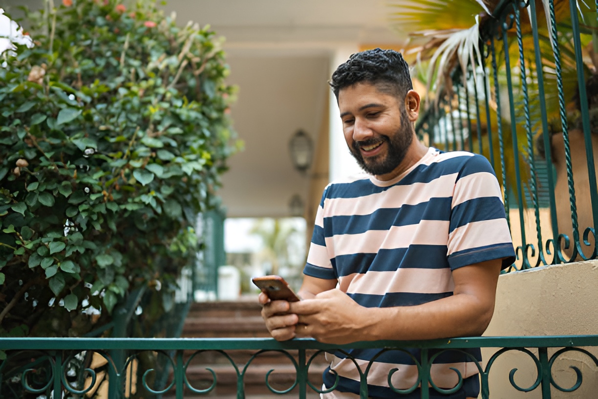man using a smartphone at the front entrance of a home
