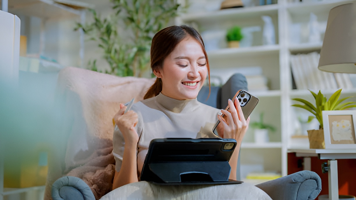 woman using a smartphone and tablet in a living room